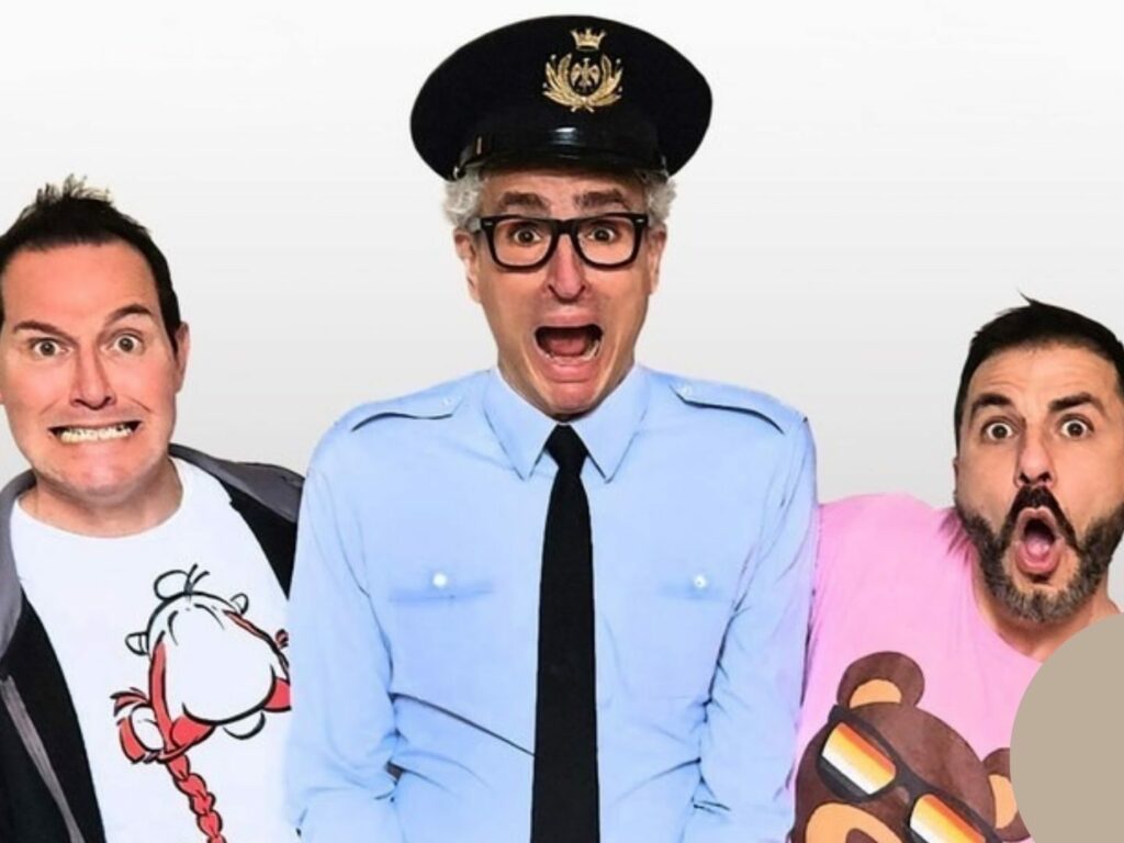 Baby Boomer, spettacolo comico teatrale: tre protagonisti con espressioni esilaranti, al centro un uomo vestito da poliziotto con cappello e occhiali neri.