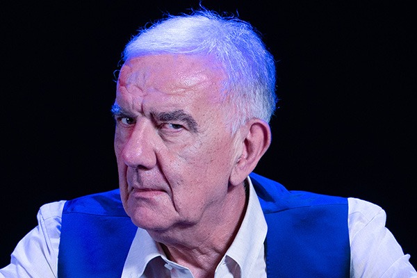 Primo piano di Gene Gnocchi con camicia bianca e gilet blu, protagonista dello spettacolo comico Una crepa nel crepuscolo, proposto da On Art a teatro.